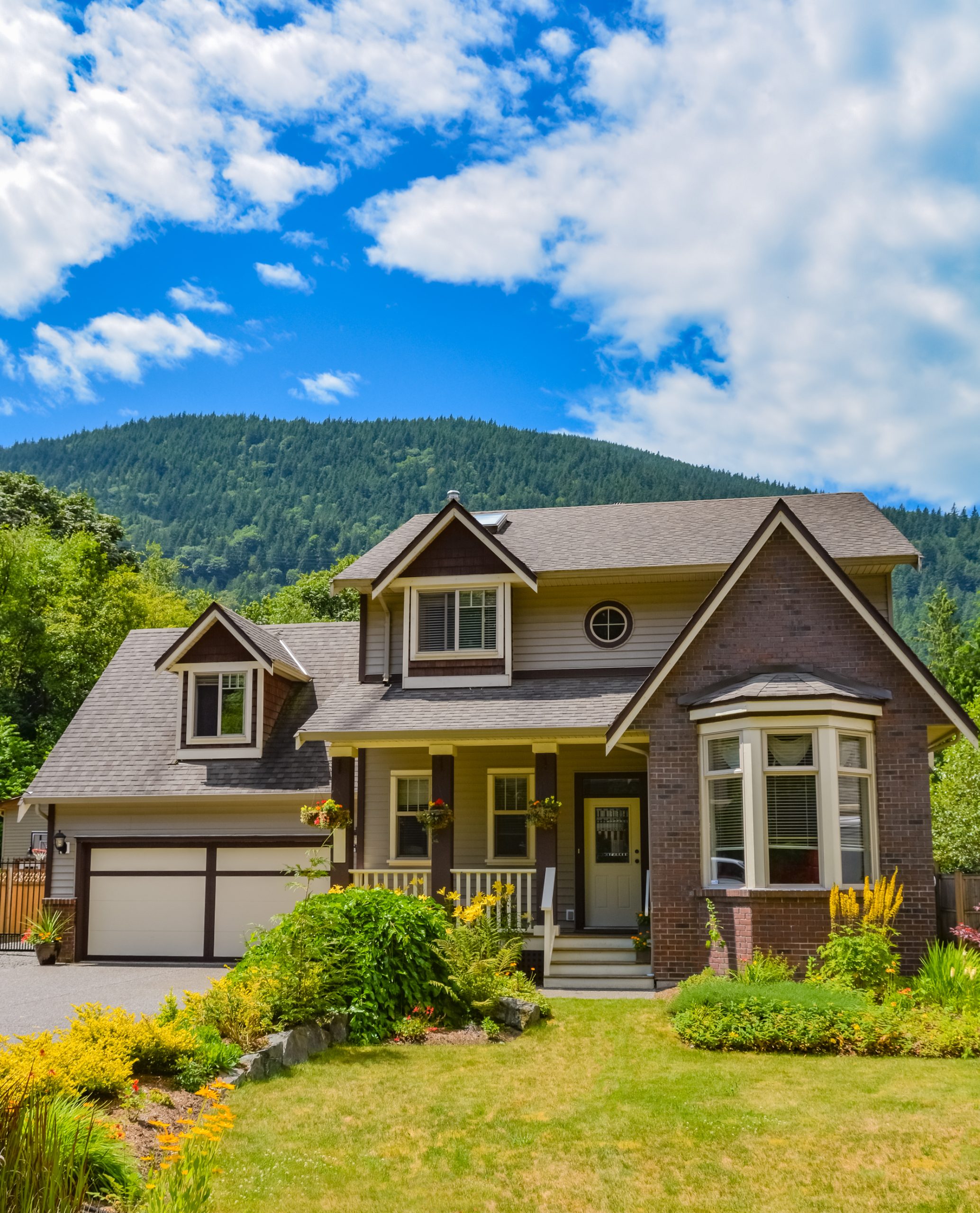 Big family house with wide garage and decorated front yard with mounting and blue sky background